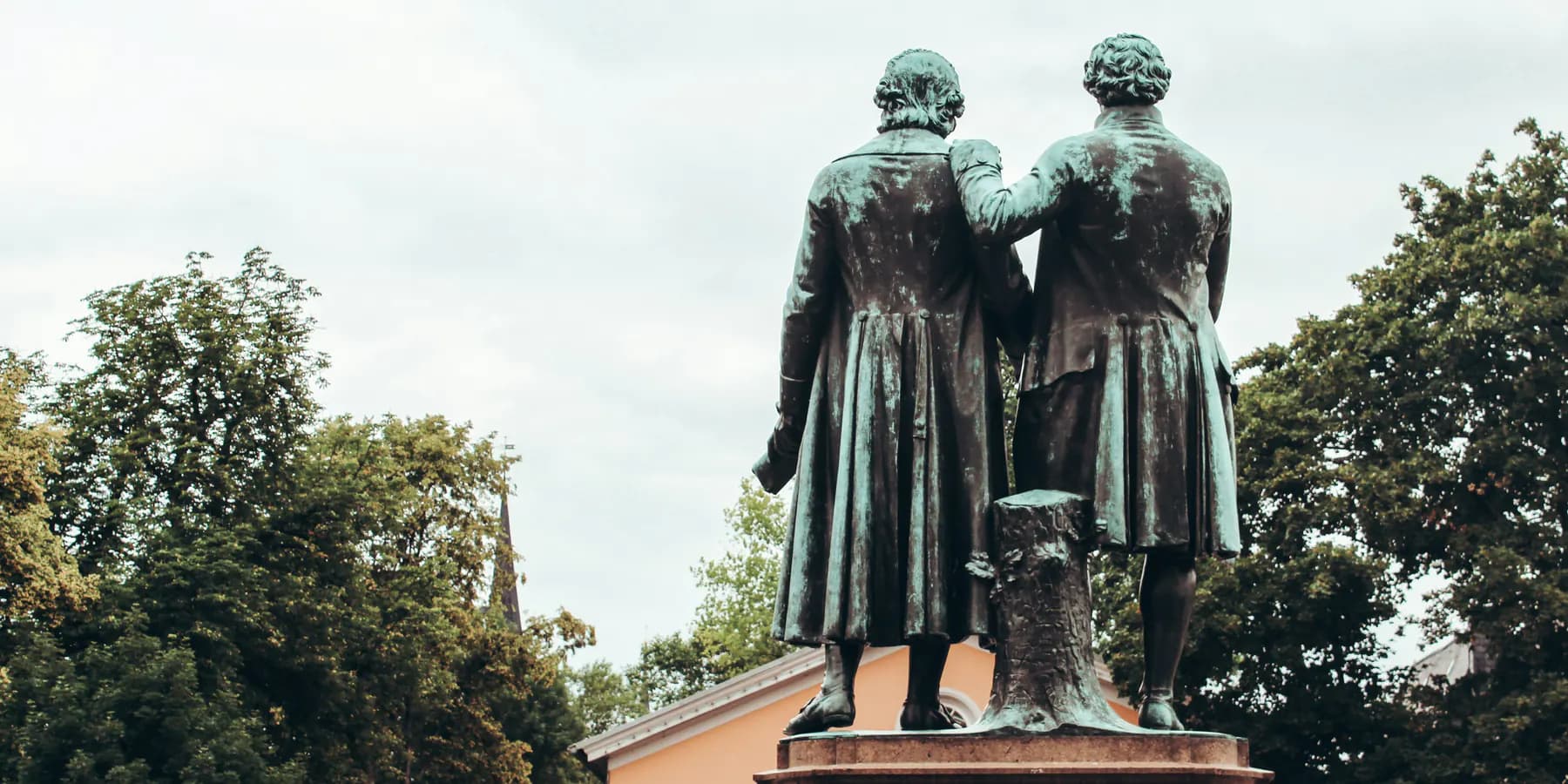 Bronzene Dichterstatuen vor einem historischen Gebäude