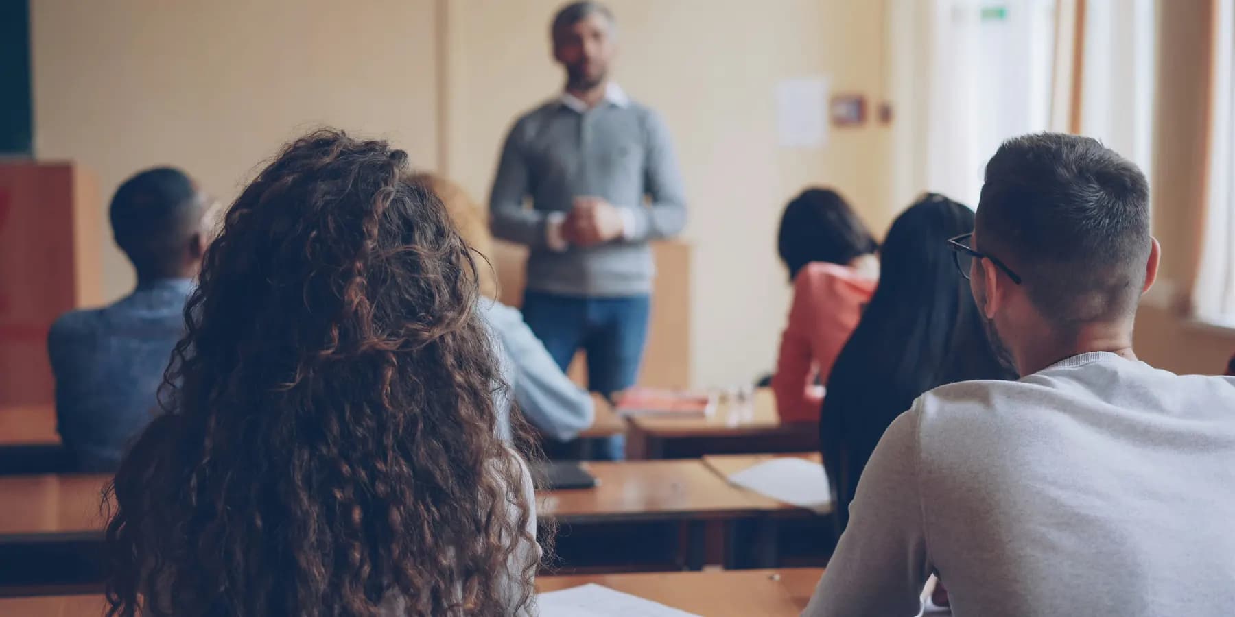 Lehrkraft unterrichtet Schülerinnen und Schüler in einem Klassenraum