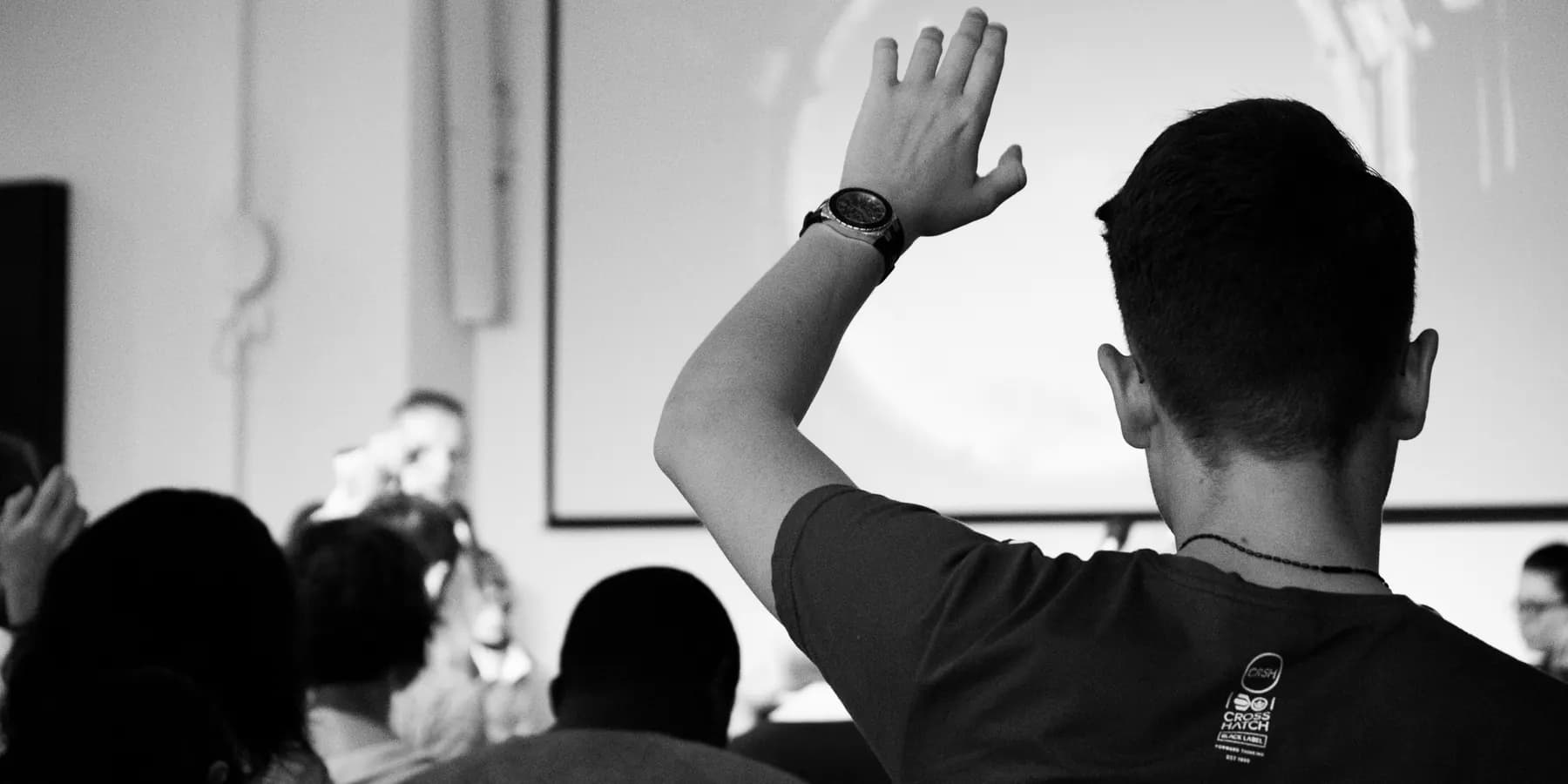 Person mit erhobener Hand während eines Vortrags