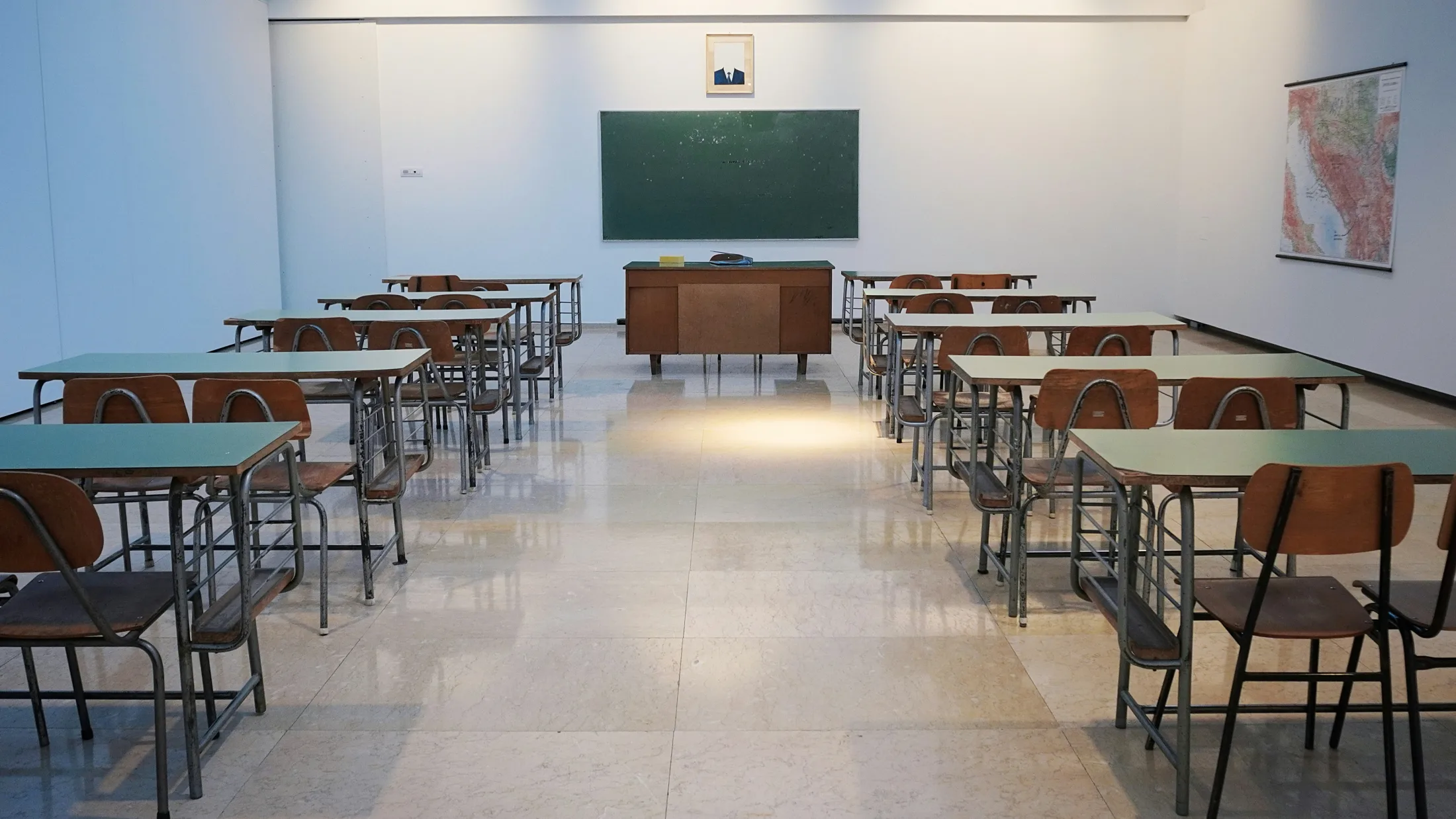 Leerer Klassenraum mit einzeln gestellten Tischen und Tafel vor Klausurbeginn