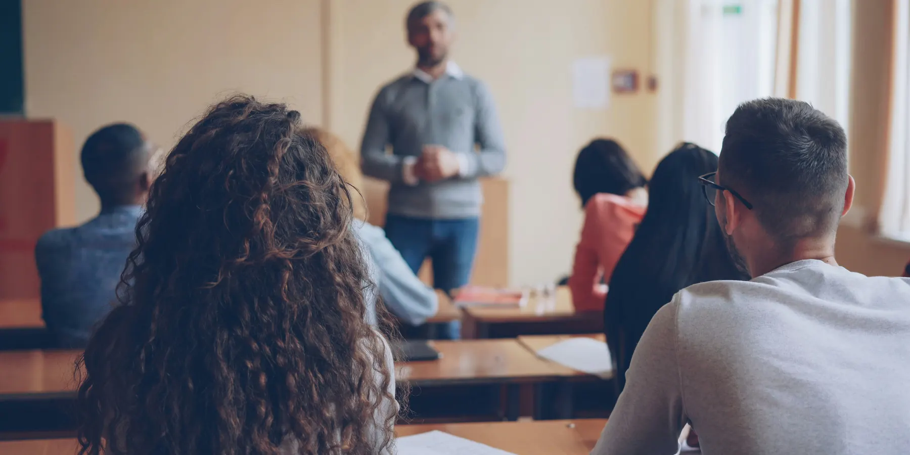 Lehrkraft unterrichtet Schülerinnen und Schüler in einem Klassenraum